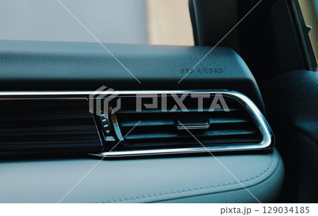 Close up view of a sleek car dashboard showing airbag indicator and ventilation 129034185