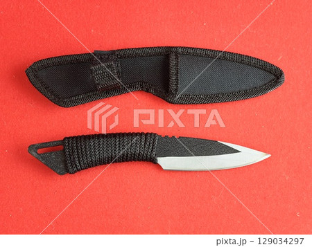 Throwing knife scorpion and black case. Traditional Japanese cold weapon on a red background. Throwing knife scorpion and black case. Traditional Japanese cold weapon on a red background. 129034297
