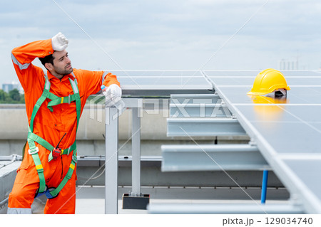 Professional technician worker or engineer stand near solarcell panel and relax with action of tired in area of factory or rooftop building. 129034740