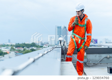 Professional technician worker or engineer use walkie-talkie to discuss with co-worker near solar cell panel during check or maintenance in area of factory or rooftop building. Professional technician worker or engineer use walkie-talkie to discuss with co-worker near solar cell panel during check or maintenance in area of factory or rooftop building. 129034760