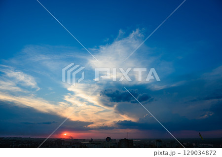 Dramatic sunset sky over city skyline with clouds. 129034872