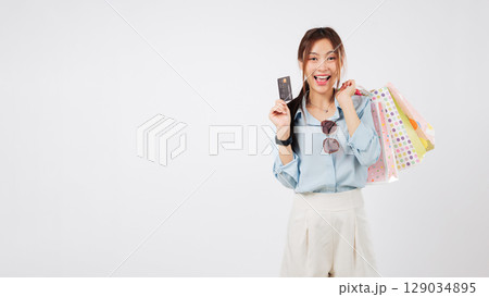 Happy woman shop with bag holds finance card, excitedly showing a store credit card and shopping bags after a good payment experience, headshot isolated studio white background Happy woman shop with bag holds finance card, excitedly showing a store credit card and shopping bags after a good payment experience, headshot isolated studio white background 129034895