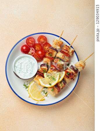 Grilled chicken skewers with lemon wedges, cherry tomatoes and yogurt sauce top view Grilled chicken skewers with lemon wedges, cherry tomatoes and yogurt sauce top view 129034915