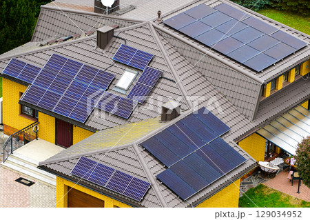 Modern Yellow Brick House with Multiple Roof-Mounted Solar Panels for Sustainable Energy Use 129034952
