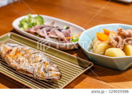 焼き魚と肉じゃが、カツオのたたきが並ぶ夕食の食卓 焼き魚と肉じゃが、カツオのたたきが並ぶ夕食の食卓 129035996