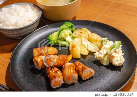 にんじんを巻いた豚肉の肉巻きと副菜が並ぶ夕食プレート 129036314