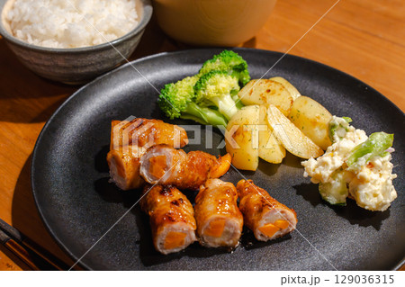 にんじんを巻いた豚肉の肉巻きと副菜が並ぶ夕食プレート にんじんを巻いた豚肉の肉巻きと副菜が並ぶ夕食プレート 129036315
