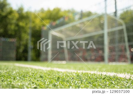 Empty soccer goal on field with artificial green grass. Summer outdoor game. 129037100