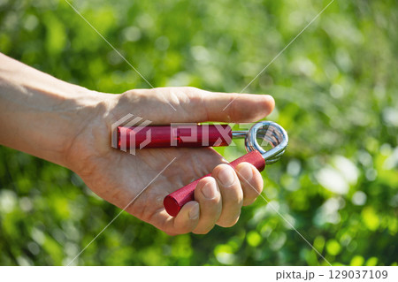 Sports red metal expander in man's hand. 129037109