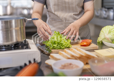 Close-up of a chef's hands preparing lettuce on a wooden cutting board Close-up of a chef's hands preparing lettuce on a wooden cutting board 129038571