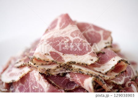 スパイスの黒い縁どりと柔らかなピンク色のコントラスト - 華やかなアンデスポークパストラミスライス 129038903