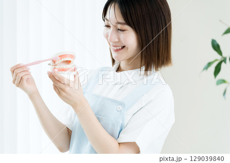 歯ブラシと歯の模型を持つ歯科スタッフの女性 歯ブラシと歯の模型を持つ歯科スタッフの女性 129039840