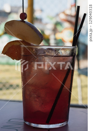 Strawberry mojito on the table with orange and apple, children's playground in the background Strawberry mojito on the table with orange and apple, children's playground in the background 129040318