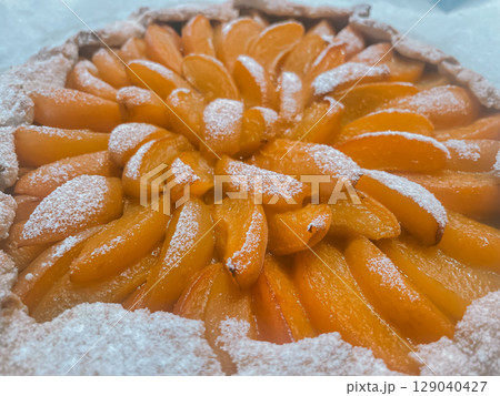Delicious galette with bright juicy orange apricot slices generously dusted with powdered sugar Delicious galette with bright juicy orange apricot slices generously dusted with powdered sugar 129040427