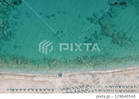 Seaside landscape with crystal-clear water, underwater relief, white sand and beach umbrellas Seaside landscape with crystal-clear water, underwater relief, white sand and beach umbrellas 129040548