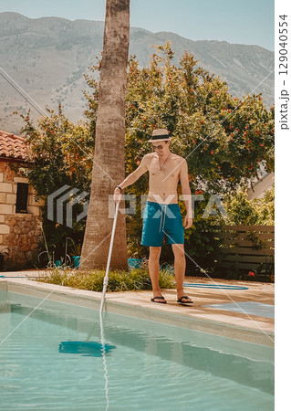 Happy young man cleaning his own pool in Greek nature Happy young man cleaning his own pool in Greek nature 129040554