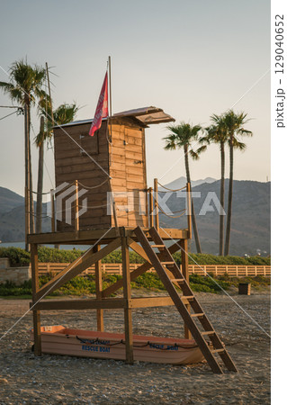 Lifeguard hut on a Greek beach, rescue boat underneath, palm trees and beautiful landscape of Crete 129040652