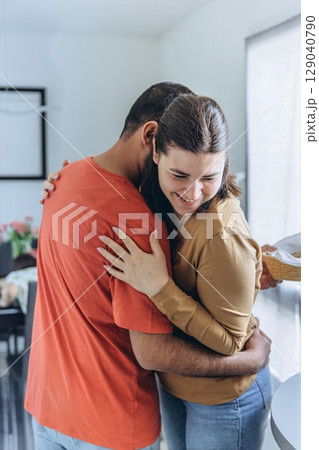 Happy couple hugging in the kitchen during a warm moment of affection and connection. Domestic lifestyle, family love, and emotional bonding at home 129040790