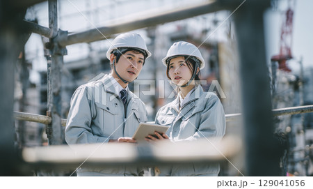 建設現場でタブレットを見る男女のビジネスパーソン 129041056