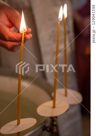 A close-up of three lit candles used during a traditional Orthodox baptism ceremony 129041598