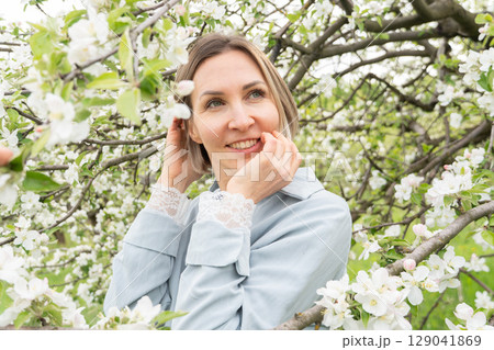 Smiling middle-aged woman in a soft blue outfit. Spring-themed wellness campaigns, skincare branding, and mental health awareness 129041869