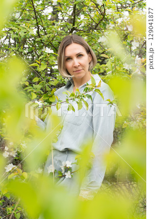Smiling middle-aged woman in a light blue outfit. Natural cosmetics, wellness retreats, and mental health awareness 129041877