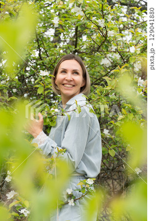 Smiling middle-aged woman in a light blue outfit. Natural cosmetics, wellness retreats, and mental health awareness Smiling middle-aged woman in a light blue outfit. Natural cosmetics, wellness retreats, and mental health awareness 129041880