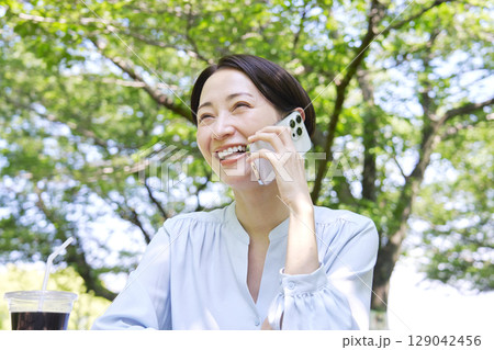 屋外でスマートフォンで電話する女性 屋外でスマートフォンで電話する女性 129042456