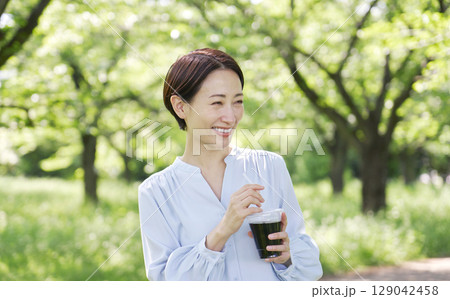 屋外でアイスコーヒーを飲む40代女性 屋外でアイスコーヒーを飲む40代女性 129042458