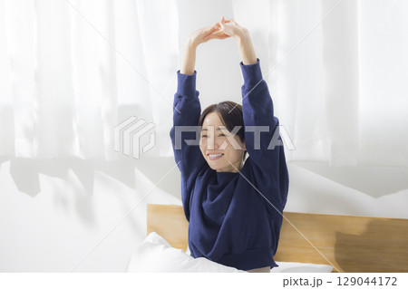 ベッドで伸びをする女性 ベッドで伸びをする女性 129044172
