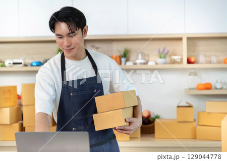 E-commerce. Employee carrying packages in shipping department. 129044778