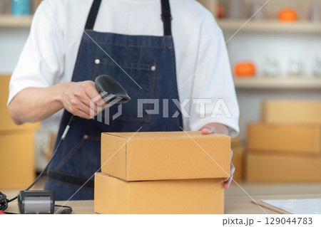 E-commerce. Employee scanning package in shipping department. E-commerce. Employee scanning package in shipping department. 129044783