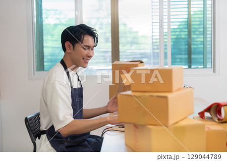 Home Office. Young entrepreneur managing packages and logistics from his desk. 129044789