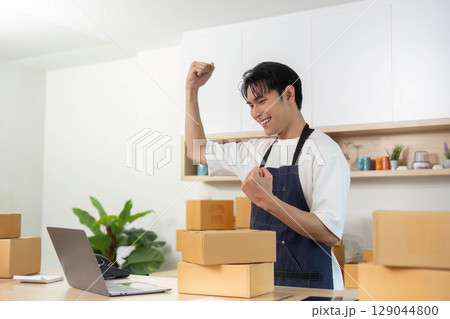 E-commerce success. Young man celebrating achievement while working on laptop. 129044800