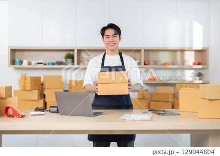 E-commerce Success. Young man celebrating achievement in online business with packages. 129044804