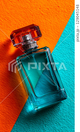 Aqua and orange backdrop highlighting a sleek teal perfume bottle design 129045148