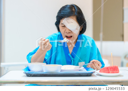 Senior Woman eating food after eye surgery in hospital . Eye disease, Cataract, Glaucoma, Age Related Macular Degeneration, Diabetic Retinopathy, Lasik, World Glaucoma day and health treatment Senior Woman eating food after eye surgery in hospital . Eye disease, Cataract, Glaucoma, Age Related Macular Degeneration, Diabetic Retinopathy, Lasik, World Glaucoma day and health treatment 129045533