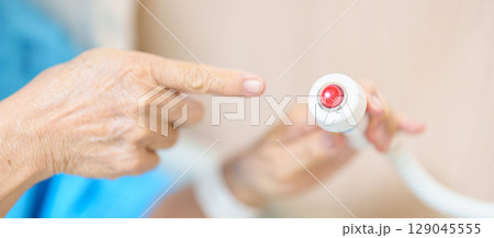 Elderly woman Patient hand holding and pressing emergency button in hospital room, calling nurse in emergency case. Professional Medical system and Safety Alert Elderly woman Patient hand holding and pressing emergency button in hospital room, calling nurse in emergency case. Professional Medical system and Safety Alert 129045555