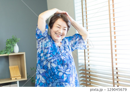 室内で腕のストレッチをする60代のシニア女性 室内で腕のストレッチをする60代のシニア女性 129045679
