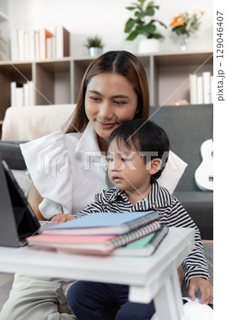Focused Learning. Child Watching Tablet with Mother in Cozy Living Room 129046407