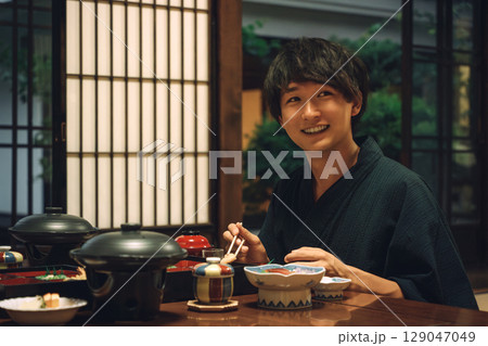 温泉旅館・旅館での食事・部屋食・夕食を食べる浴衣姿の男性 129047049