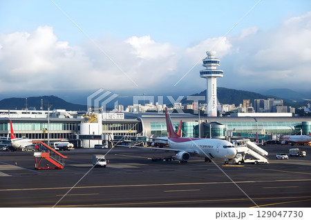 Jeju International Airport with Airplanes on the Runway and Scenic Mountain Background in Clear Day 129047730