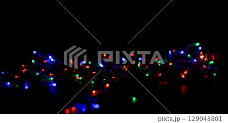 Messy jumble of multicolor christmas lights on black background, festive holiday decoration with red, green, and blue colors overlay Messy jumble of multicolor christmas lights on black background, festive holiday decoration with red, green, and blue colors overlay 129048801