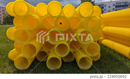 Bright yellow pipes stacked in outdoor area for construction needs, construction scene shows raw materials, construction visuals support infrastructure, urban planning, and industrial design content 129050692