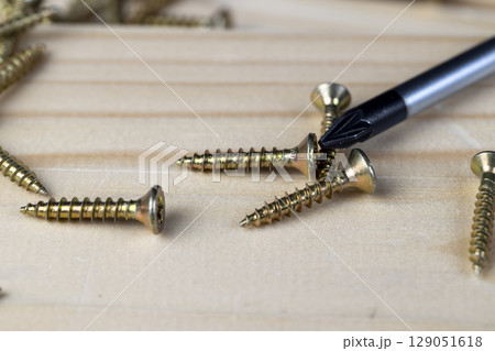 screwdriver and screws for fixing wood lying on a board, a group of tools for construction , close up 129051618