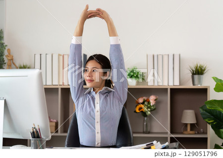 Office Syndrome: Young woman stretching at desk to relieve tension and improve posture 129051796