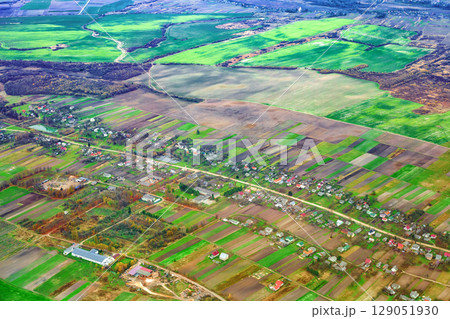 Aerial view of rural landscape with patchwork agricultural fields and tiny houses along road, farms, plant, lumberyard, school 129051930