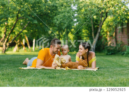 Family Lying On Blanket Outdoors With Teddy Bears 129052925