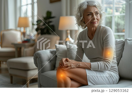Senior Woman on Couch with Joint Pain in Knee and Elbow 129053162