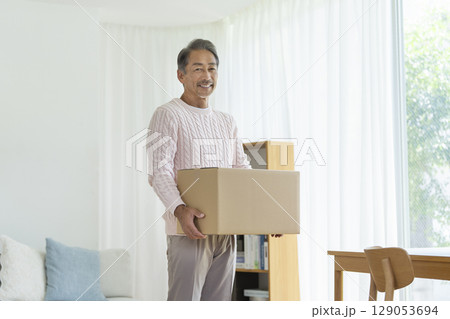 カメラ目線で笑顔のダンボール箱を持ったシニア男性　引越し・断捨離　イメージ　 129053694